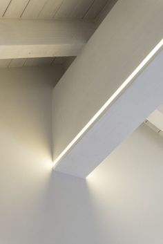 an empty room with white walls and wooden beams on the ceiling is lit by two lights