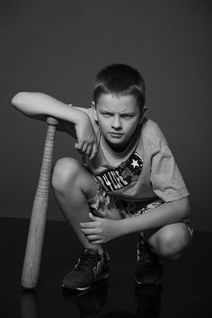 a young boy sitting on the floor with a baseball bat