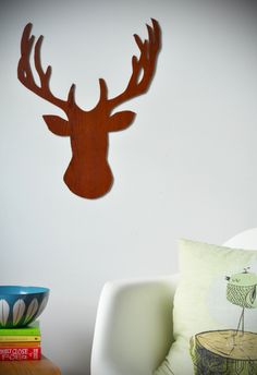 a wooden deer head mounted to the wall above a white chair in a living room