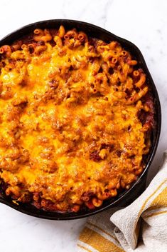 a skillet filled with macaroni and cheese on top of a white counter