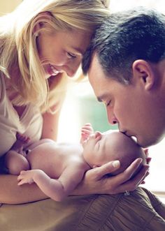 a man and woman holding a baby in their lap while they look at each other