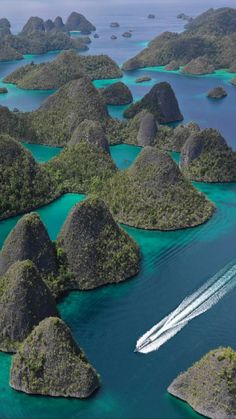 an aerial view of many small islands in the ocean with a speedboat passing by