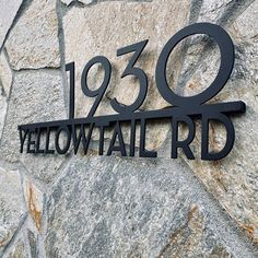 a black metal sign on the side of a stone wall that reads yellowtail rd