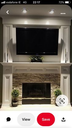 a tv mounted above a fireplace with potted plants on the mantel below it