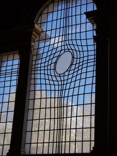 a large window with an artistic design on it's glass pane, in front of a blue sky