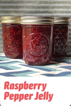 three jars filled with raspberry jelly on top of a blue and white table cloth