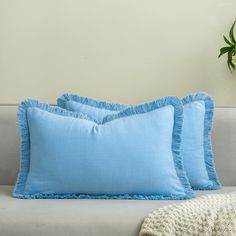 three blue pillows sitting on top of a couch next to a potted green plant