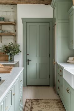 a kitchen with green cabinets and white counter tops, along with a rug on the floor