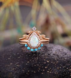 an opal and diamond ring sitting on top of a rock