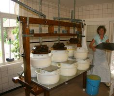 a woman is standing in front of several buckets on a shelf and holding a tray