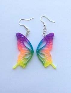 Each pair of sparkly rainbow butterfly resin earrings are handmade to order, therefore no two pairs are identical! Every jewelry piece in my shop is slightly unique and one of a kind. However, I try to match the photos as closely as possible :) Made with sterling silver plated fishhook earrings (clear rubber backing included). Hypoallergenic & nickel-free. Each butterfly wing is approximately 2 inches in length, and are made with resin, neon green, neon orange, neon pink, neon blue, neon purple, Pride Resin Jewelry, Neon Resin Earrings, Pride Accessories, Butterfly Resin, Rainbow Accessories, Pastel Cupcakes, Fishhook Earrings, Purple Neon, Jewelry Colorful