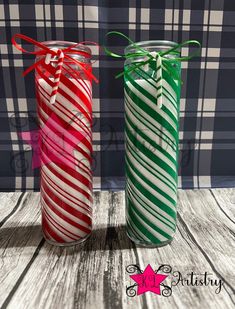 two candy canes wrapped in red, green and white paper are sitting next to each other