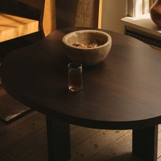 a wooden table with a bowl of cereal on it next to a vase and chair