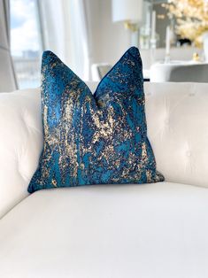 a blue and gold pillow sitting on top of a white couch