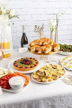 a table topped with lots of food next to a bottle of wine and plates filled with desserts