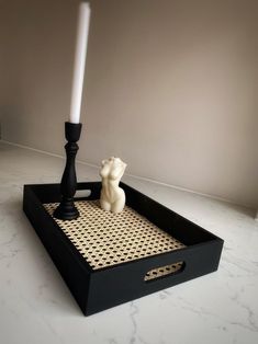 a candle holder with a bear on it and a white candle in the middle, sitting on a black tray