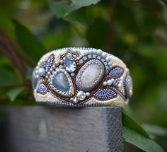 a close up of a ring on top of a piece of wood with leaves in the background