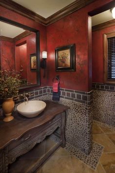 a bathroom with red walls and tile flooring is pictured in this image, there are two sinks on the counter