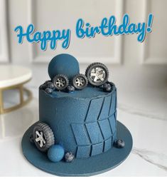 a blue birthday cake with wheels on it and the words happy birthday written in white