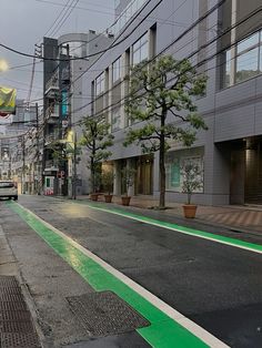 an empty city street with green lines painted on the ground and buildings in the background