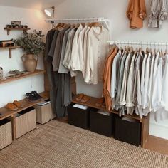 an organized closet with clothes and shoes hanging on the wall, baskets under shelves below