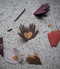 paper cutouts with hands and hearts are arranged on the floor next to some scissors