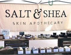 a sign that says salt and shea skin apothecary behind it is a display of soaps