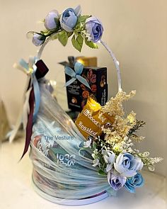 a basket filled with flowers and chocolates on top of a white counter next to a wall