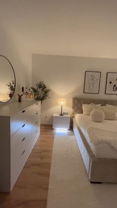 a bedroom with a bed, dresser and mirror on the wall next to each other