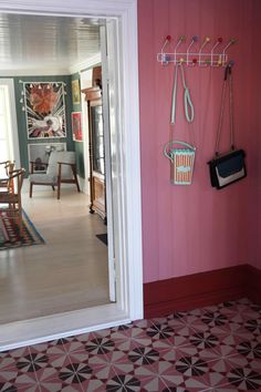 a hallway with pink walls and black and white flooring is seen through an open door