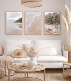 a living room filled with white furniture and paintings on the wall above it's coffee table