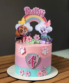 a pink and blue birthday cake with paw patrol figures on top, including the number four