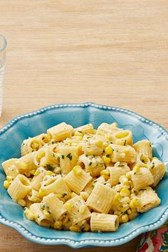 a blue bowl filled with pasta next to a glass of water