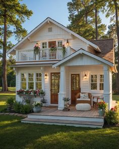 a small white house with flowers on the porch