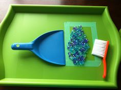 a green tray with a blue spatula, toothbrush and beaded necklaces on it