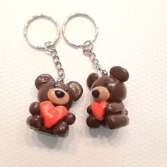 two brown teddy bears holding a heart shaped keychain on a white tablecloth