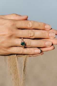 a woman's hand with an emerald ring on it