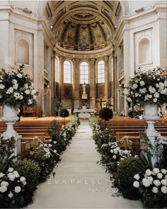 the aisle is lined with white flowers and greenery in front of an ornate alter