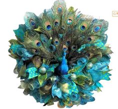 a blue and green wreath with peacocks on it's side, surrounded by feathers