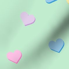 multicolored paper hearts are flying in the air on a pastel green background