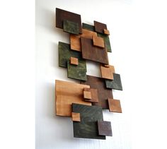 a wall sculpture made out of wood blocks on a white wall with a black and brown geometric design