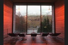 an empty room with chairs and tables in front of large windows looking out onto the mountains