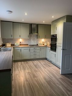 an empty kitchen with white cabinets and wood flooring is pictured in this image, there are lights on the cabinet doors