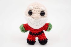 a small crocheted santa clause doll with black eyes and white beard, standing on a white background