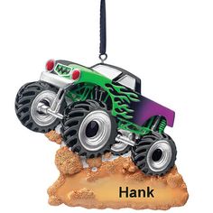 a green and purple monster truck ornament hanging from a black cord with the words hank on it