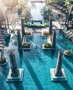 an aerial view of a swimming pool surrounded by trees and water features several stone pillars