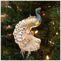 a peacock ornament hanging on a christmas tree