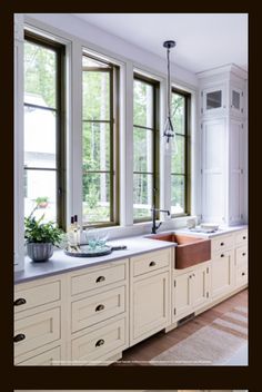 a kitchen with white cabinets and large windows