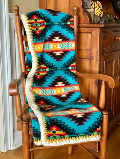 a wooden rocking chair with a blanket on it's back in front of a dresser