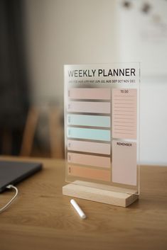 a wooden desk with a planner and pen on it, sitting next to a laptop